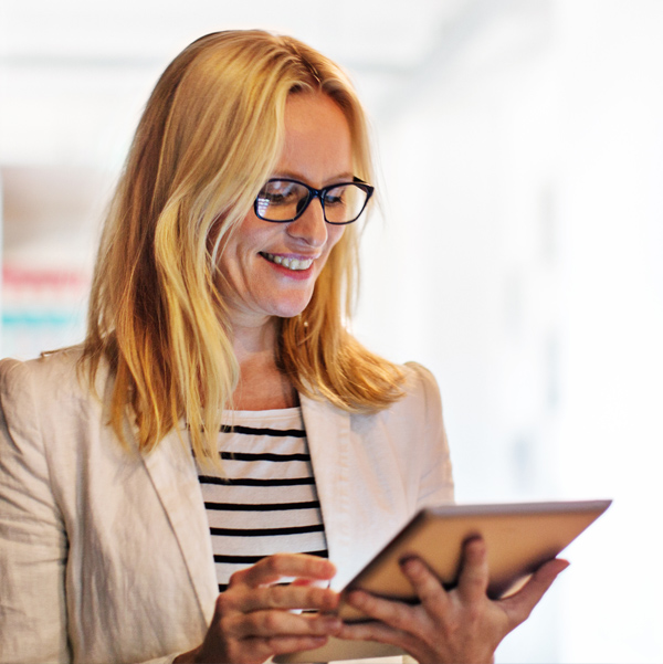 Business woman standing and looking down at a mobile device.