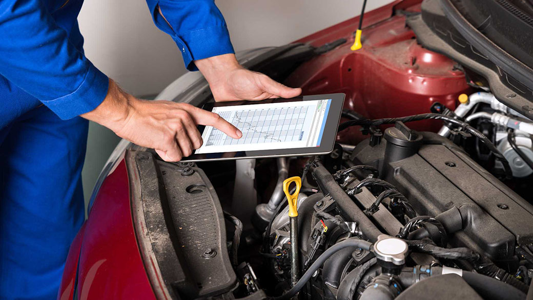 Mechanic working on a car with tablet