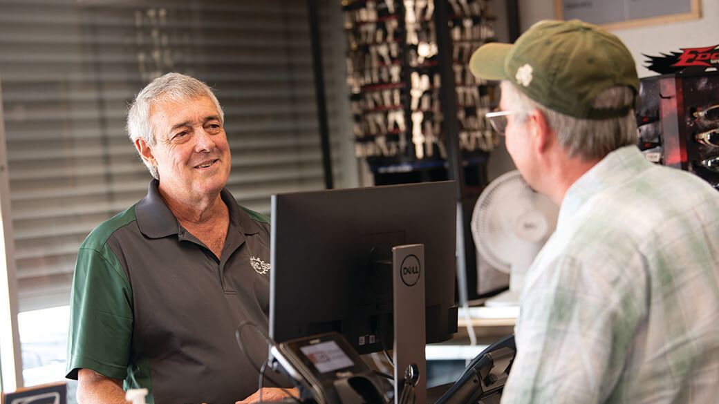 Do it Best store senior clerk smiling and chatting with a customer at the counter